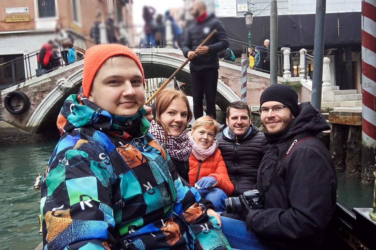 family riding in a gondola in venice 3 men and 2 eomen in winter clothes, as it was in november so rainy and cold