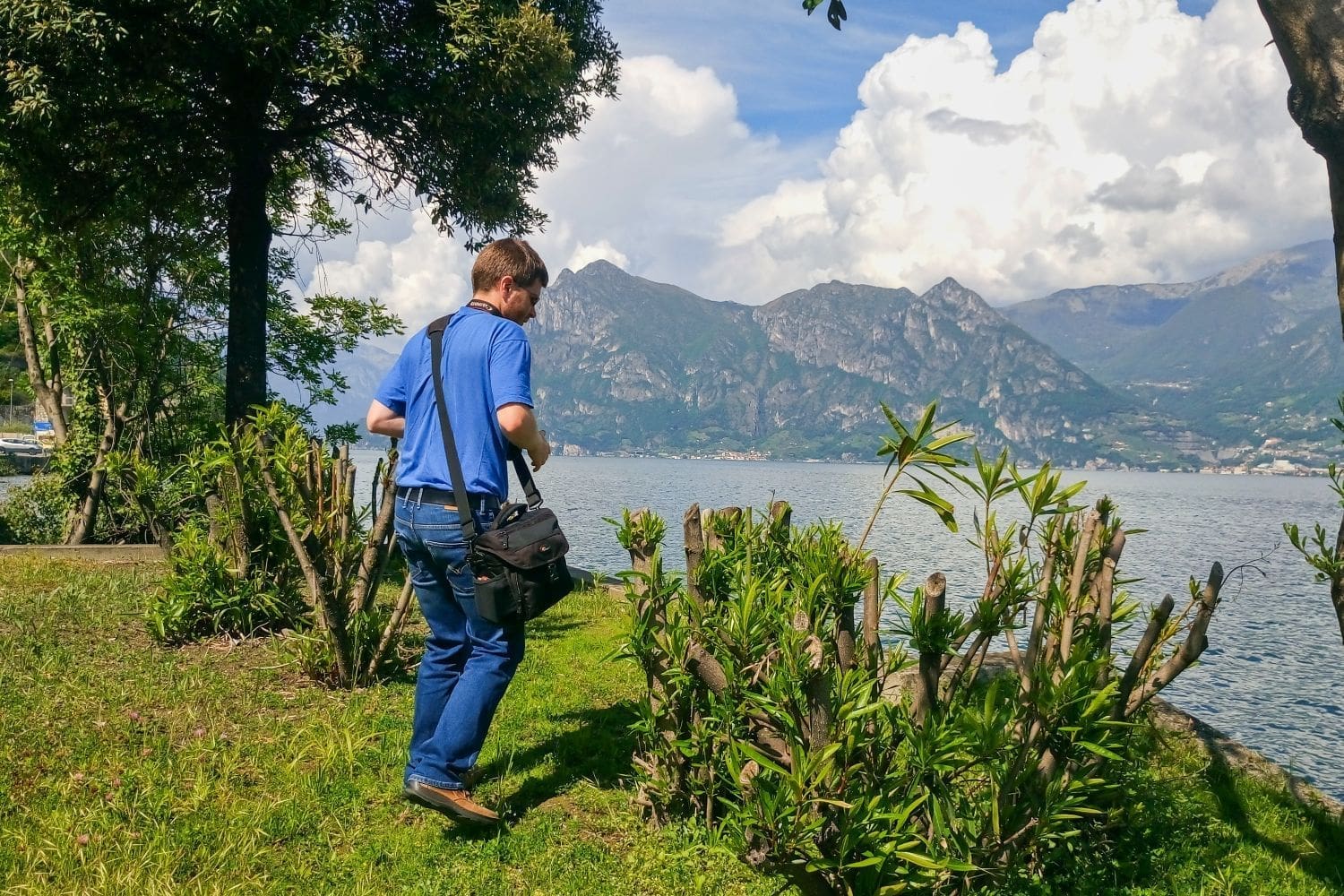 Michal on the coast of Lake Iseo in the Lombardy region with mountains and the lake in the background and very green grass and bushes in the foreground