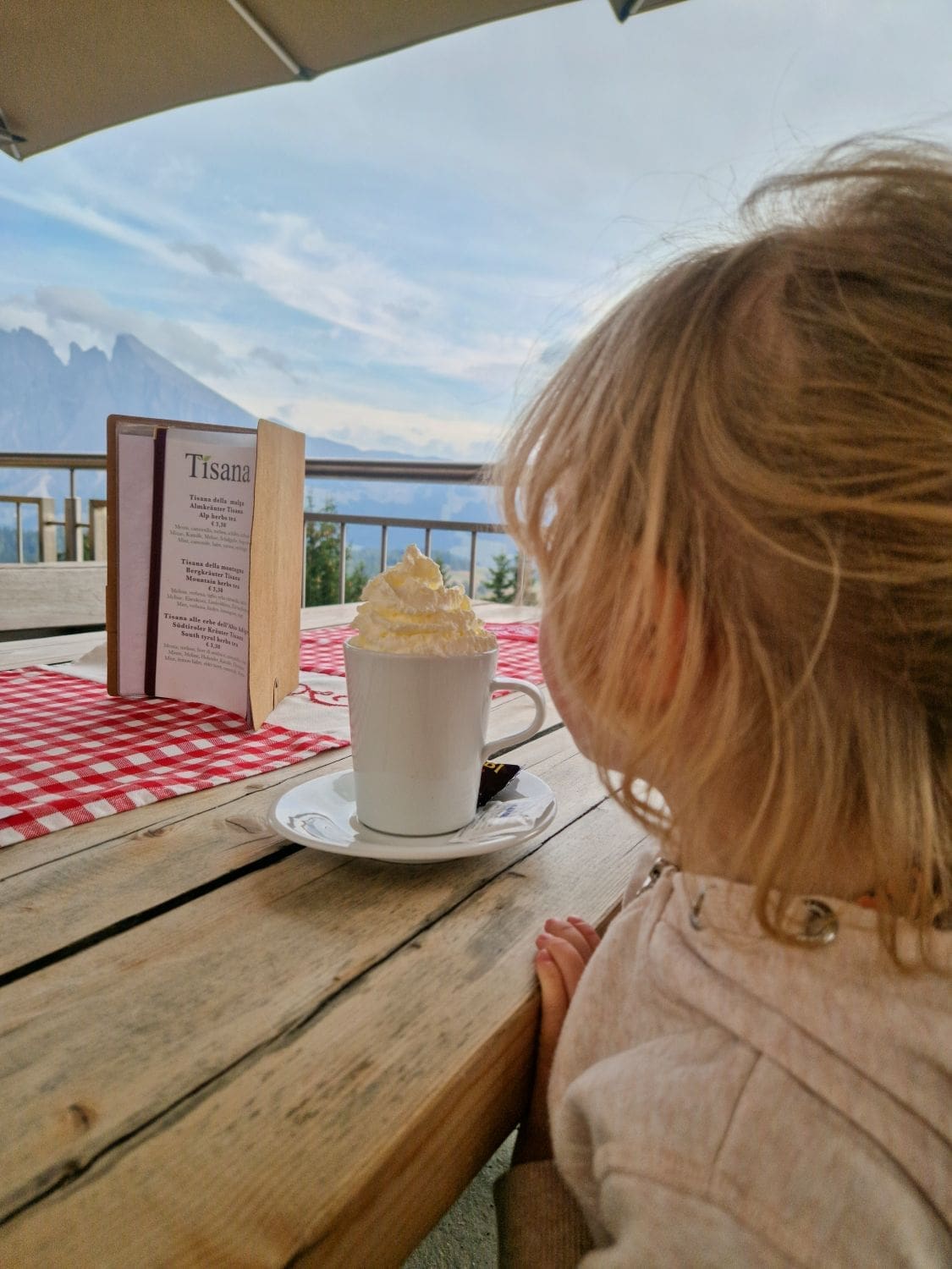 emma having cocoa in alpe di siusi in the dolomites with mountains in the background