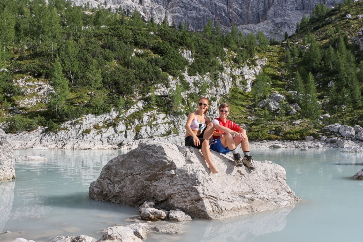 kristine and michal sitting on a rock in the milky blue lake sorapis in the dolomites