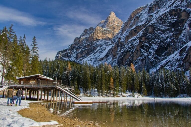 lago di braies in november, with a boat house and mountains in the background