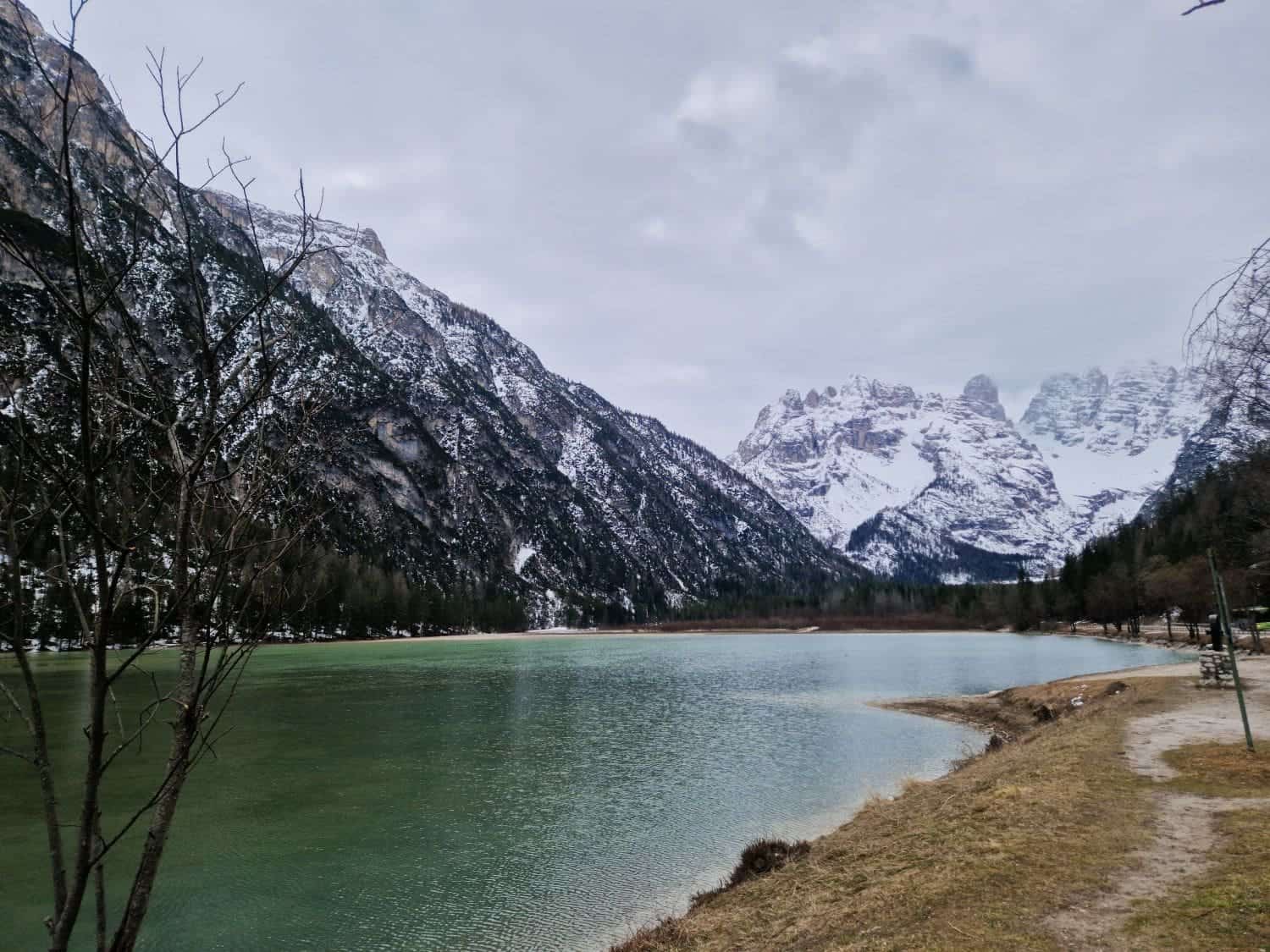 lake landro with emerald green waters with snowy mountains in the background on a cloudy day