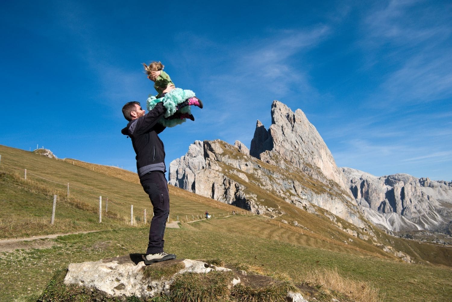 michal holding Emma with seceda mountains in the background