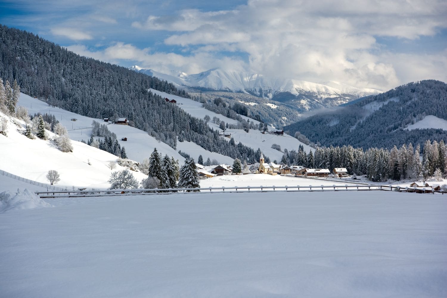 snowy view on the way to lake braies in the dolomites with a town and church visible