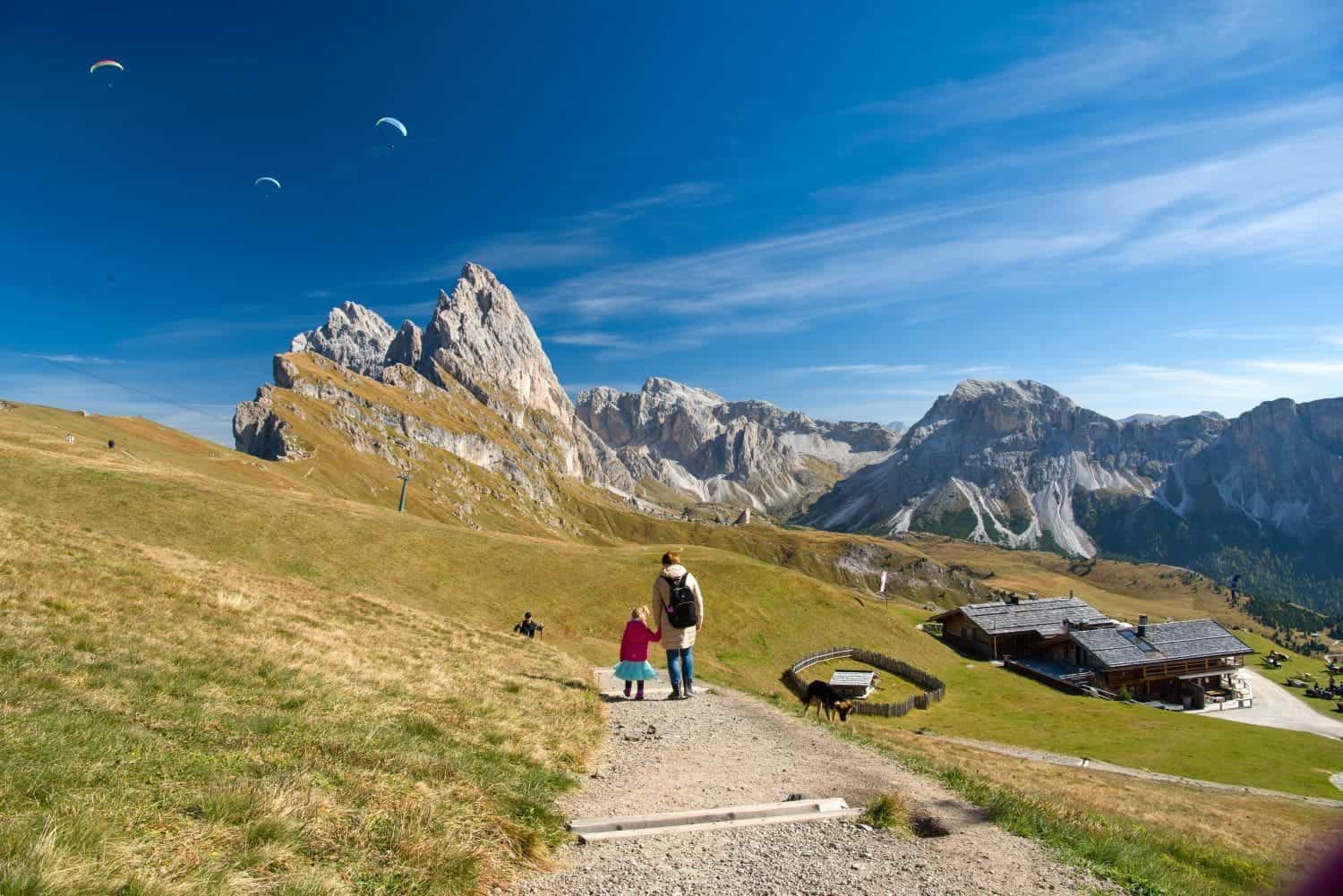 paragliders seen over the seceda mountains in the dolomites with Kristine and Emma walking towards them.