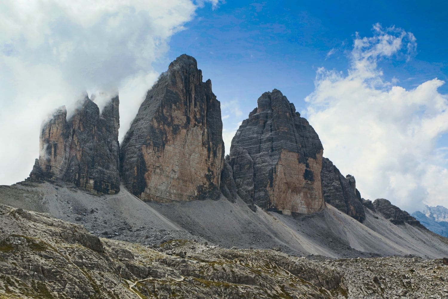 tre cime di lavaredo mountains in the dolomites with a cloud covering the leftmost one