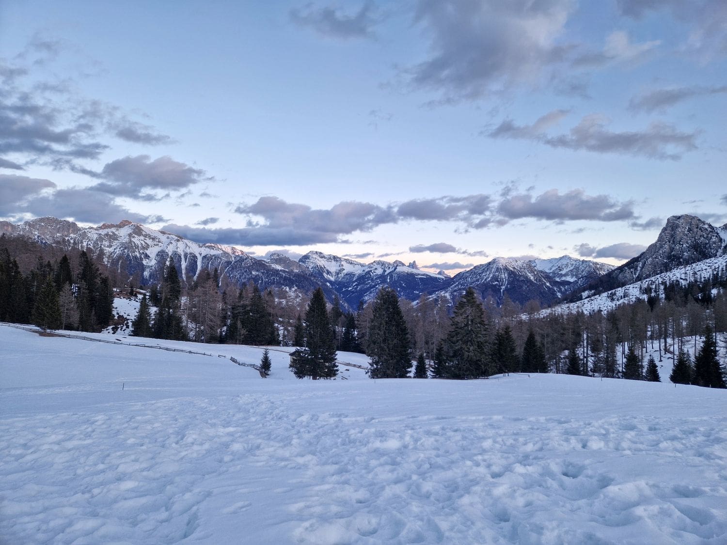 view of snowy field and snowy mountains from passo carezza in the dolomites