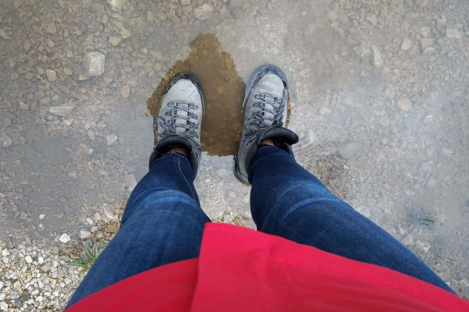standing in lake braies in dirty hiking shoes, picture taken from stomach height so legs in jeans also visible
