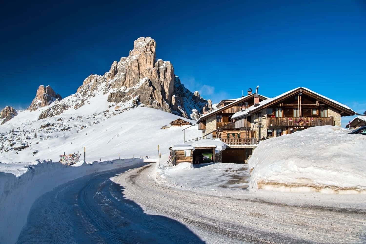 passo giau in the winter with a snowy road, snowy house, and lots and lots of snow everywhere