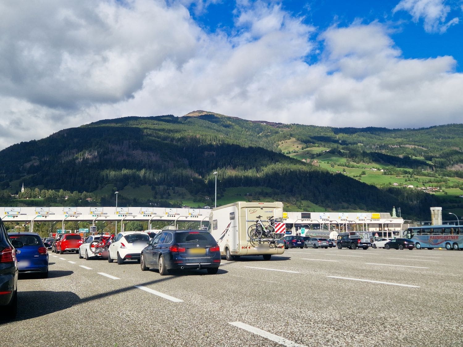 cars waiting in lines at toll booths on the autostrada brennero in the dolomites