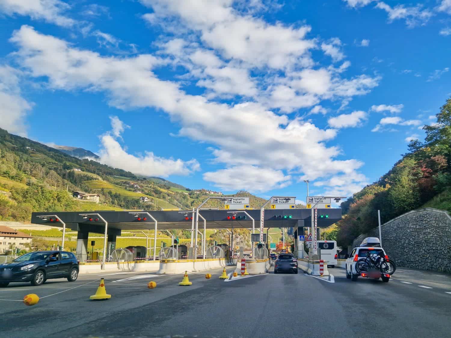 entrance gates to a toll road in italy with some cars waiting in line