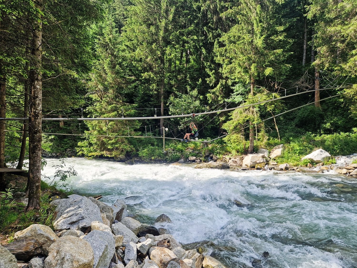 a person ziplining over a torrential mountain river in the dolomites