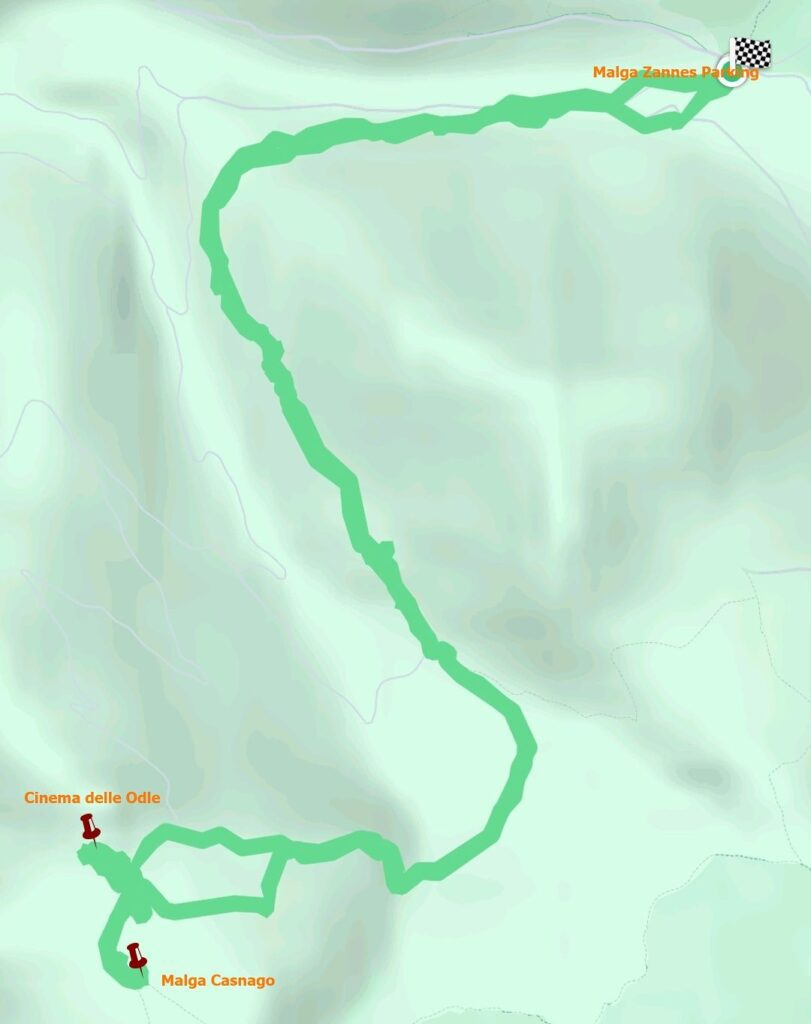 A light green hiking trail map winding through hilly terrain, starting at "Malga Zannes" and leading to "Malga Casnago" and "Cinema delle Odle" with marked trailheads and a checkered finish flag at the top right.