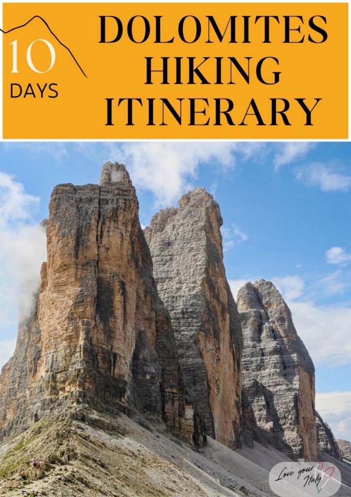 graphic that reads 10 Days Dolomites Hiking Itinerary in bold black text on a mustard yellow background above a dramatic photo of the Tre Cime di Lavaredo rock towers in the Italian Dolomites. The foreground shows tiny hikers on a rocky trail beneath the towering limestone peaks under a blue sky with light clouds and a Love your Italy logo in the corner.